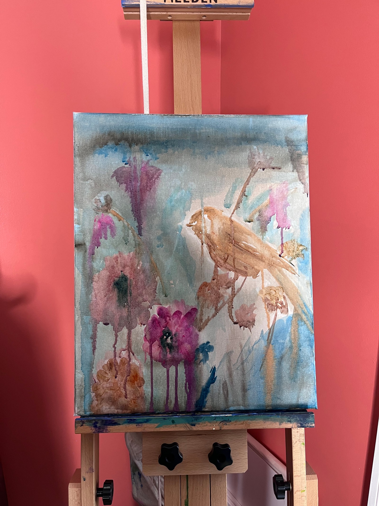 Early layers of Where the Garden Sings on the easel, with loose flower shapes and a lightly blocked-in bird
