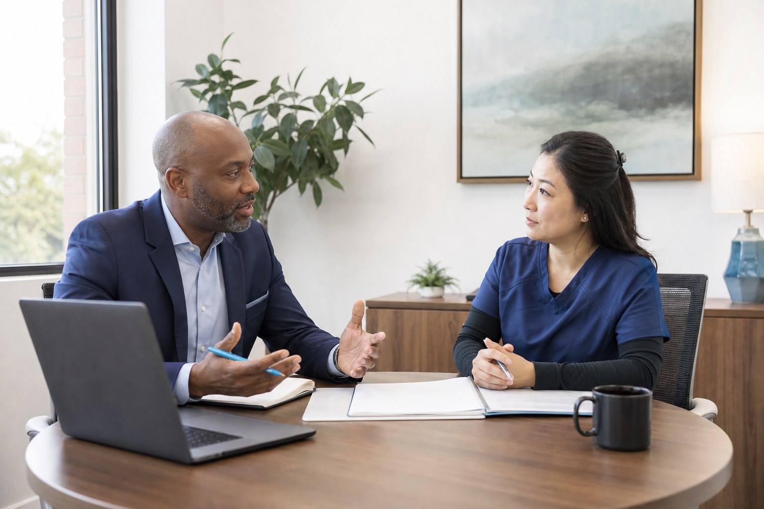 A hiring manager discussing an open role with a department supervisor beside a window