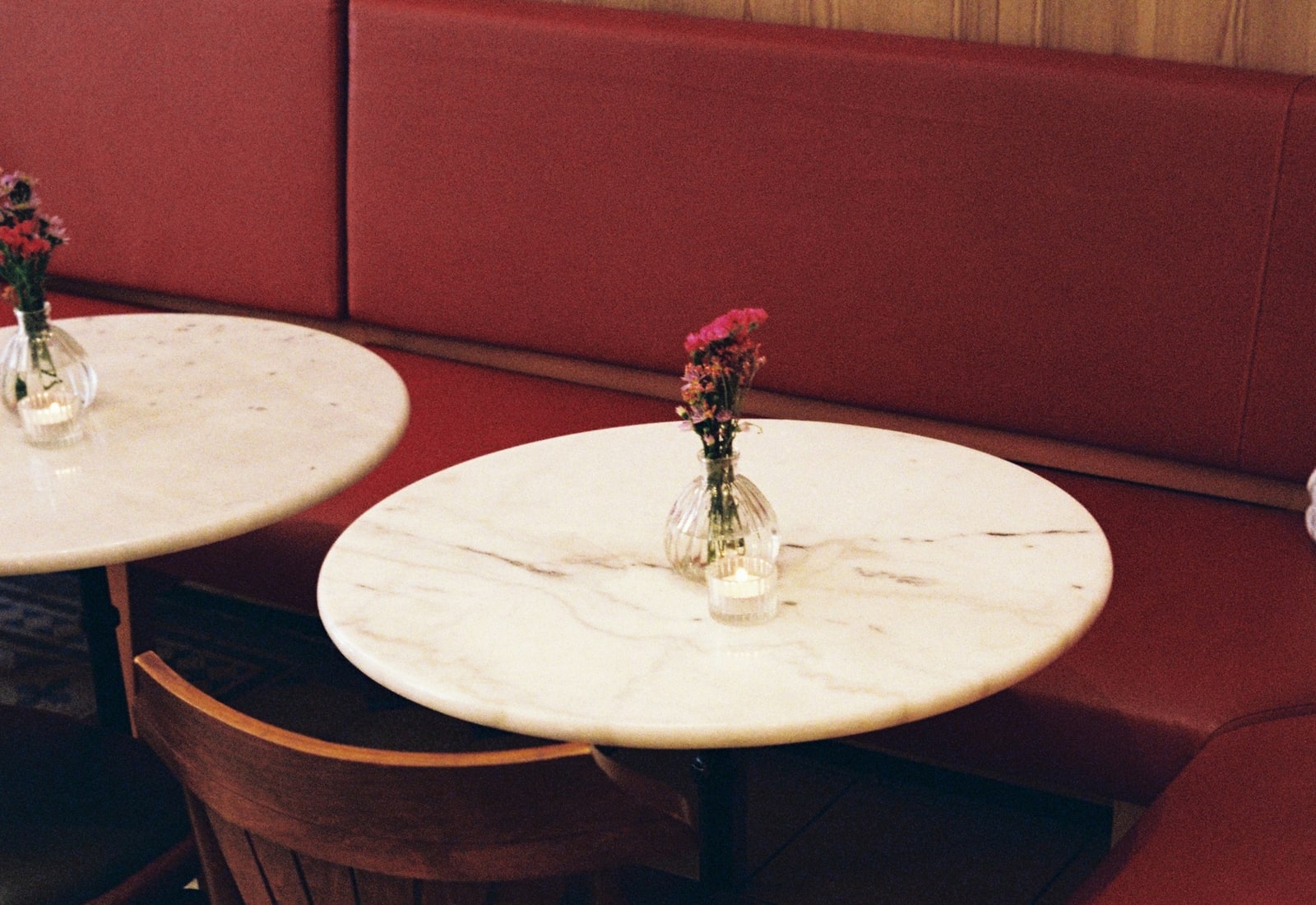 Casual restaurant booth with marble tables and small flower vases