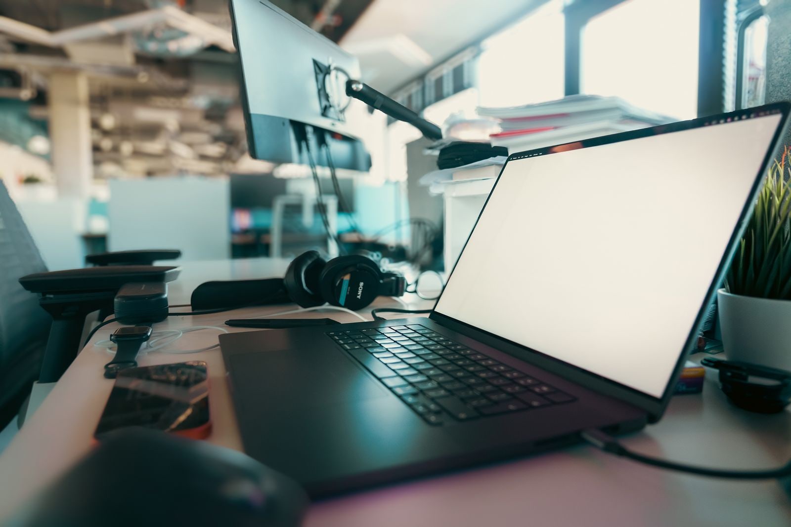 Laptop, headphones, and a phone arranged on a modern desk for an online event