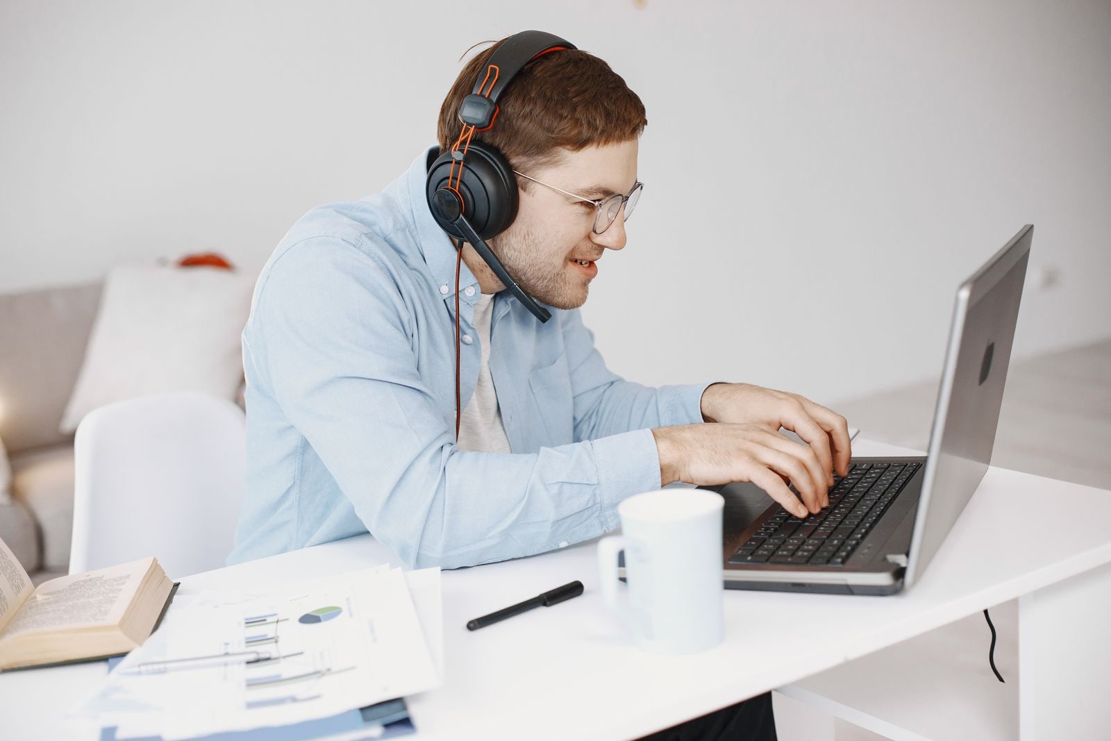 Webinar host wearing a headset and working at a laptop after an online session