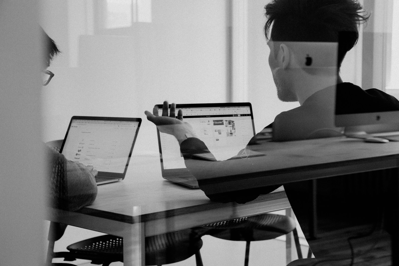 Colleagues discussing a live online presentation beside open laptops