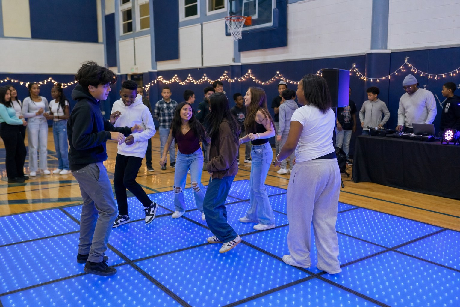Middle school students enjoying an easy group dance on a blue LED floor while friends watch from the edge