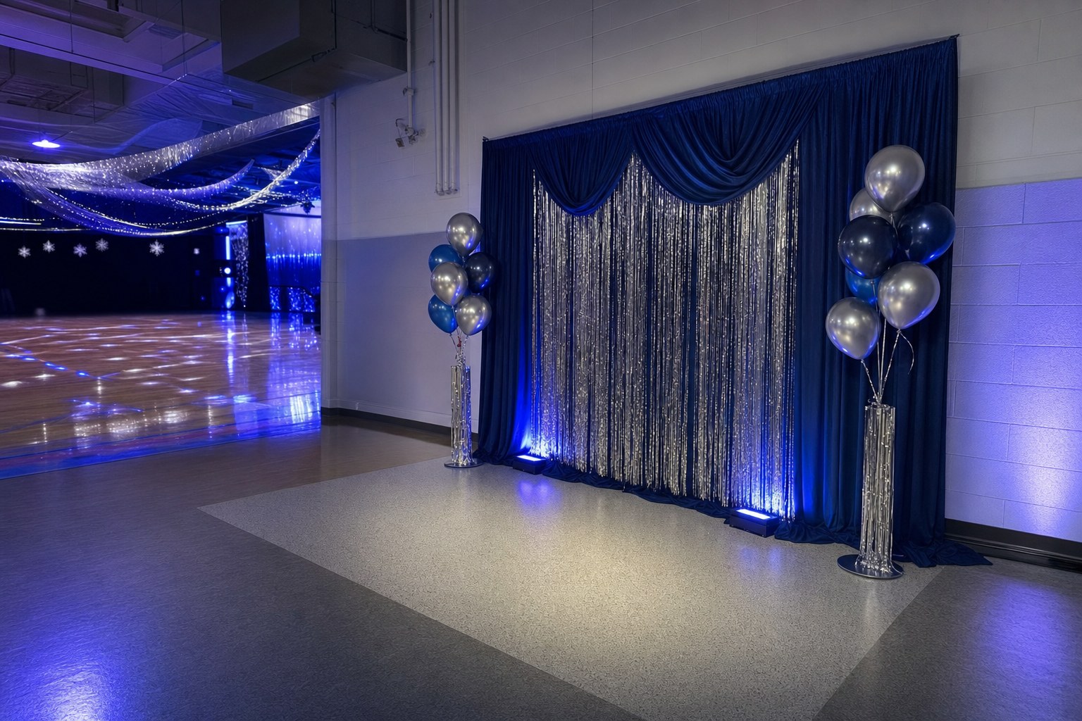 A navy and silver photo backdrop with soft blue lighting in the corner of a decorated school gym