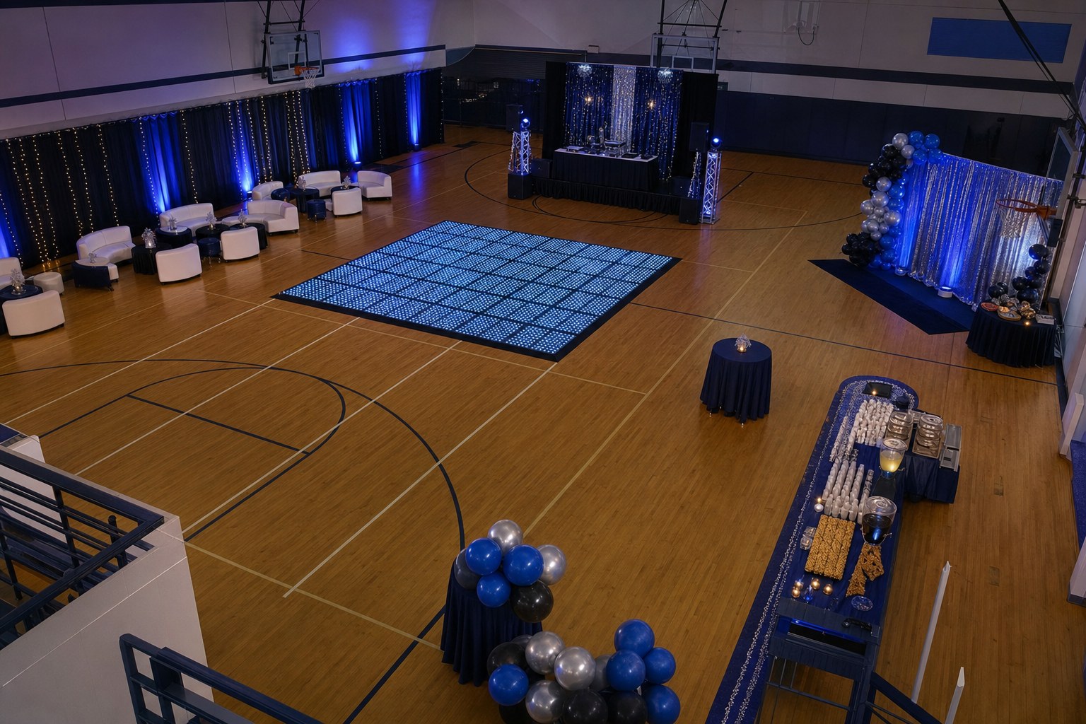 High-angle view of a school gym dance layout with an LED floor, lounge seating, photo area, refreshments, and clear walking routes