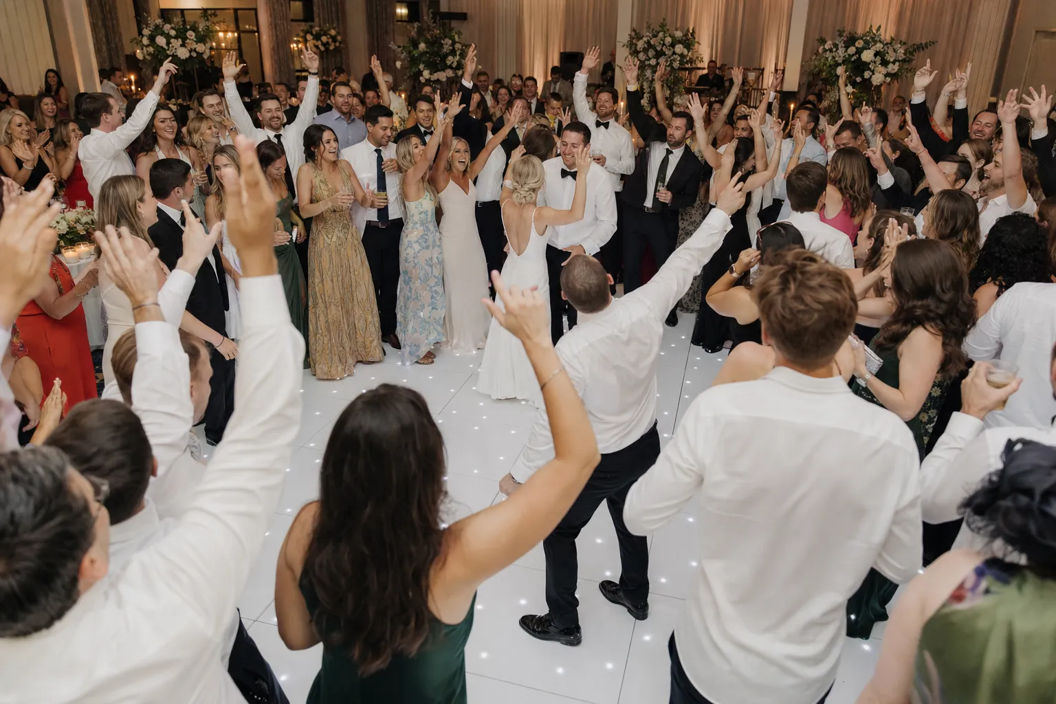 Wedding guests celebrating together on a white LED dance floor during a reception