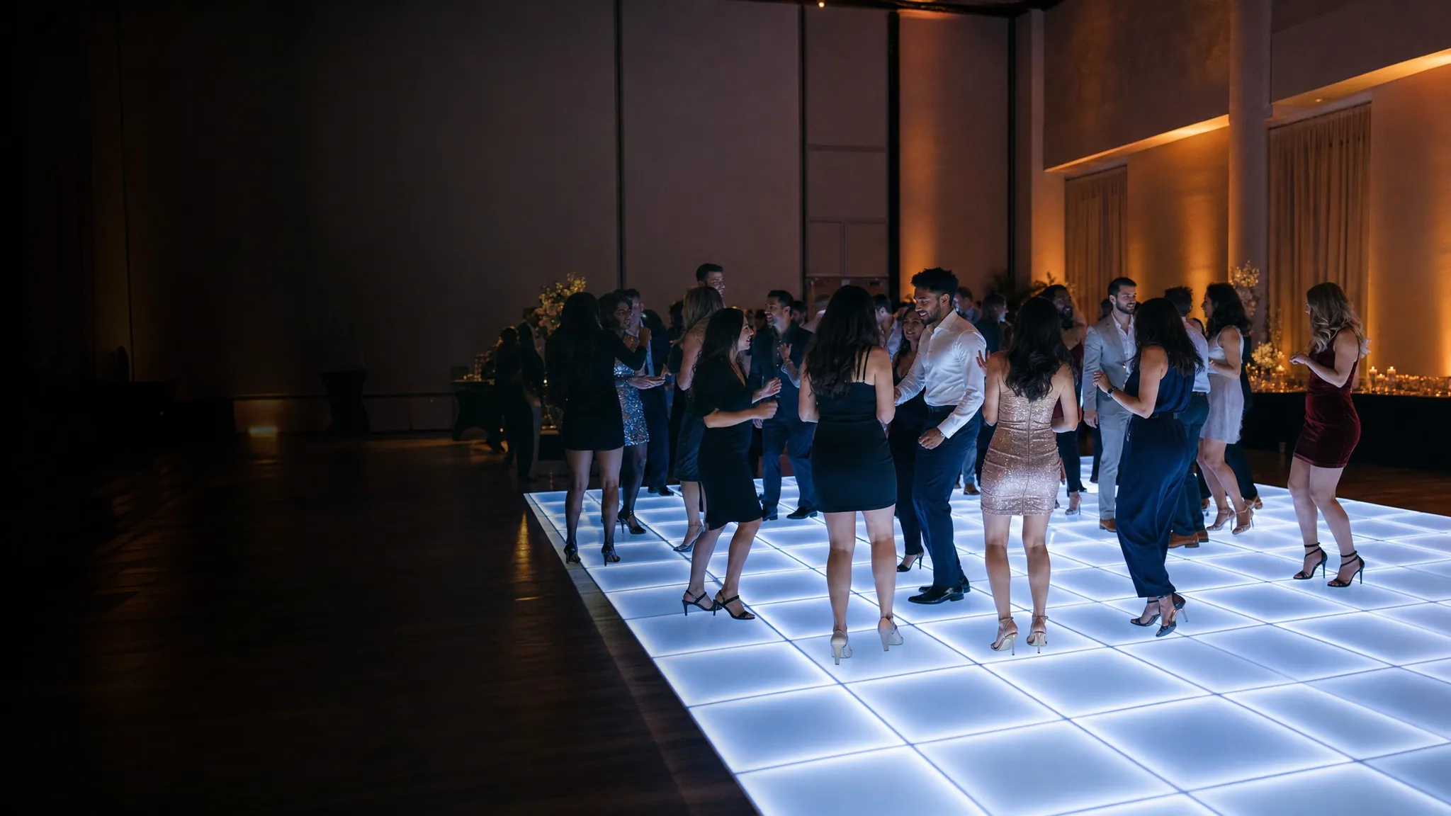 Guests dancing on a glowing white LED dance floor at an upscale indoor party