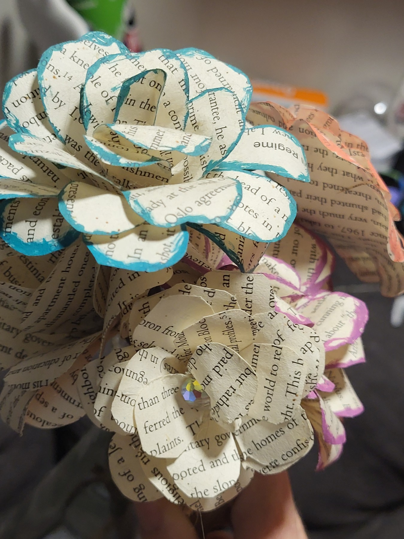 Close view of layered book-page paper flowers with colored petal edges