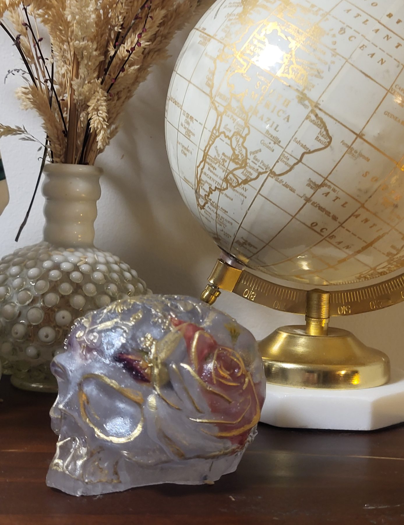 Gold-accented resin skull with dried botanical inclusions, angled view