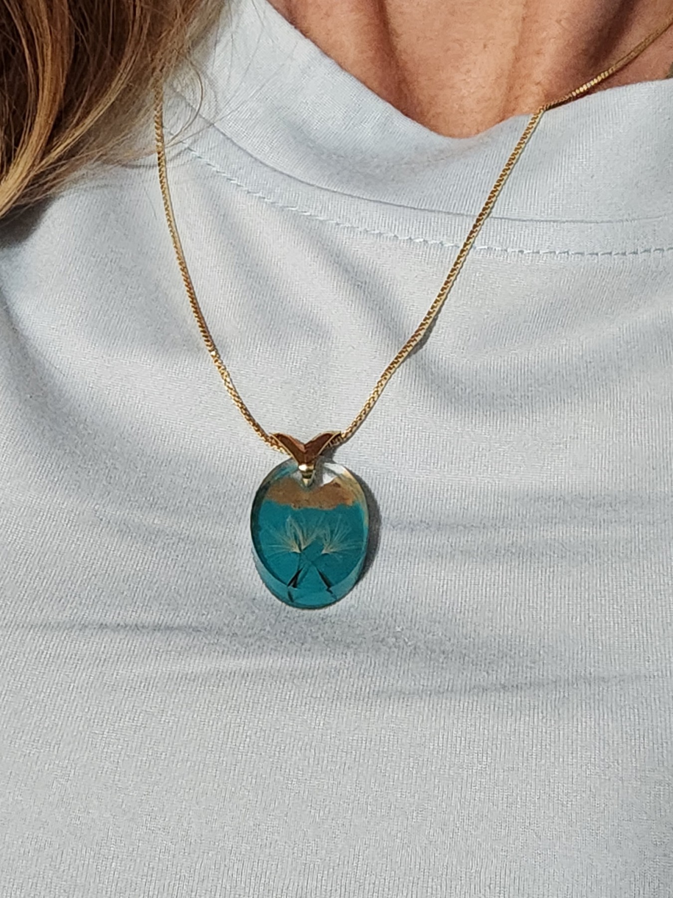 Dandelion wish pendant worn on a gold-plated chain