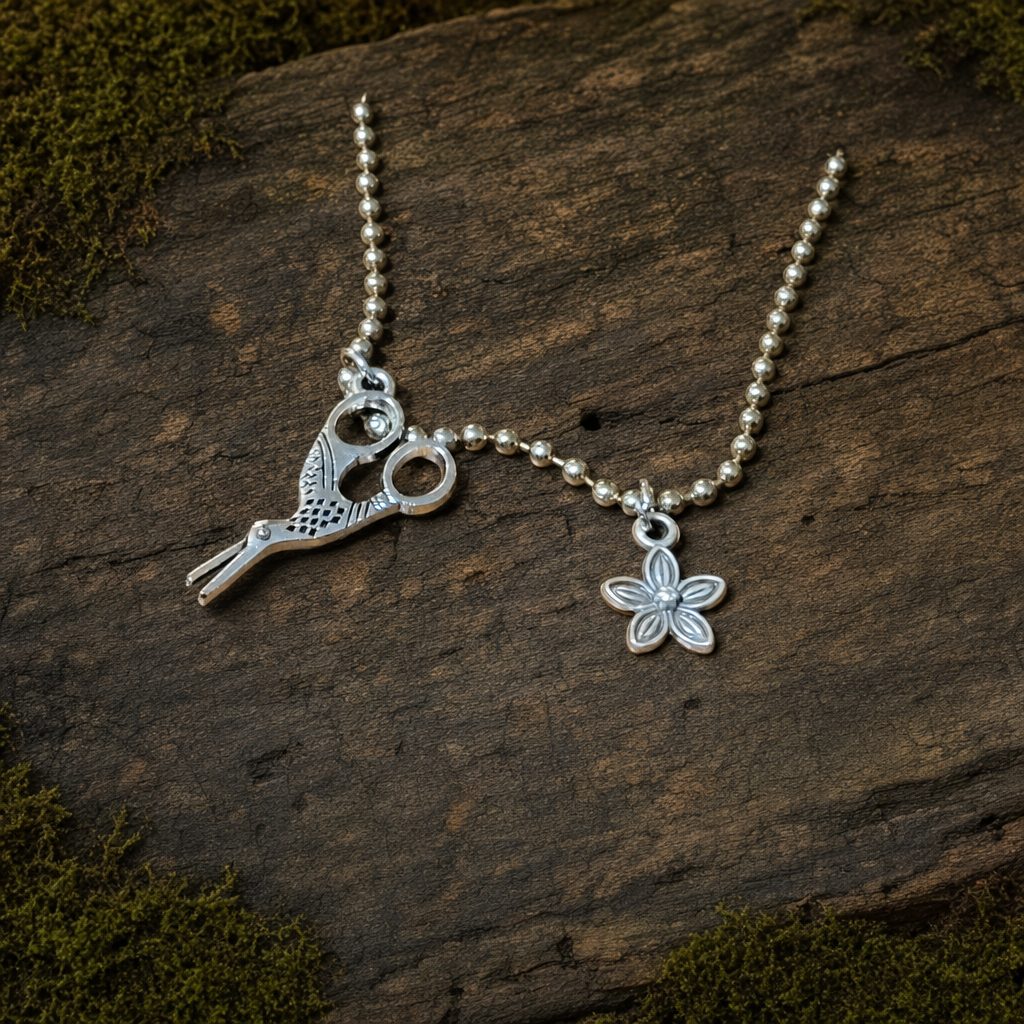 Silver-colored crane embroidery-scissors charm and silver-plated flower charm shown together on a ball chain