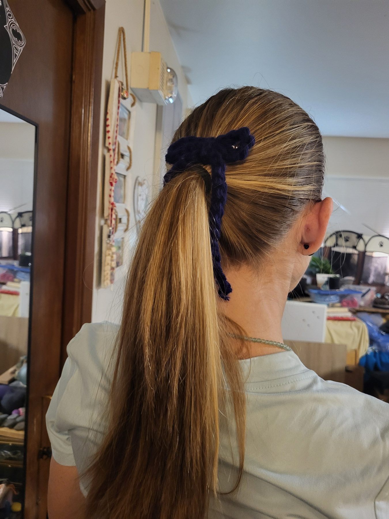 Hand-knitted navy bow securing a ponytail, shown from behind