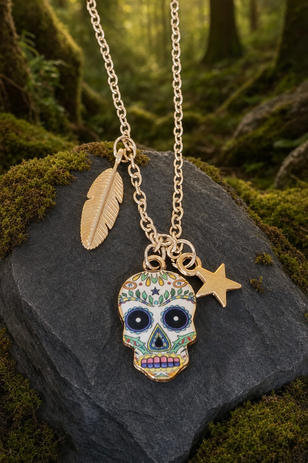 Sugar skull pendant with feather and star charms on a chain, displayed against dark stone and moss