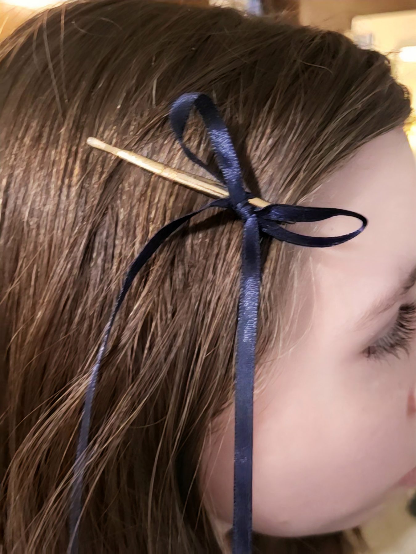 Small navy satin bow worn at the side of the hair