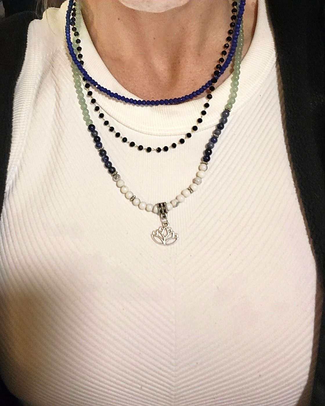 Three separately sold necklaces layered together: short faceted lapis lazuli, middle black onyx satellite chain, and long mixed-stone lotus necklace
