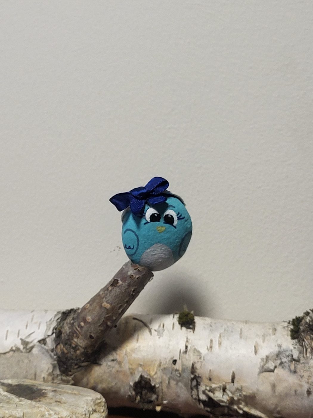 Small blue bird painted stone mounted on a birch branch
