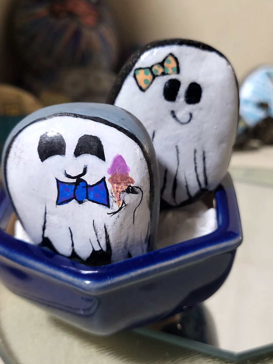 Two smiling white ghost stones, one with a bow tie and ice cream and one with a hair bow