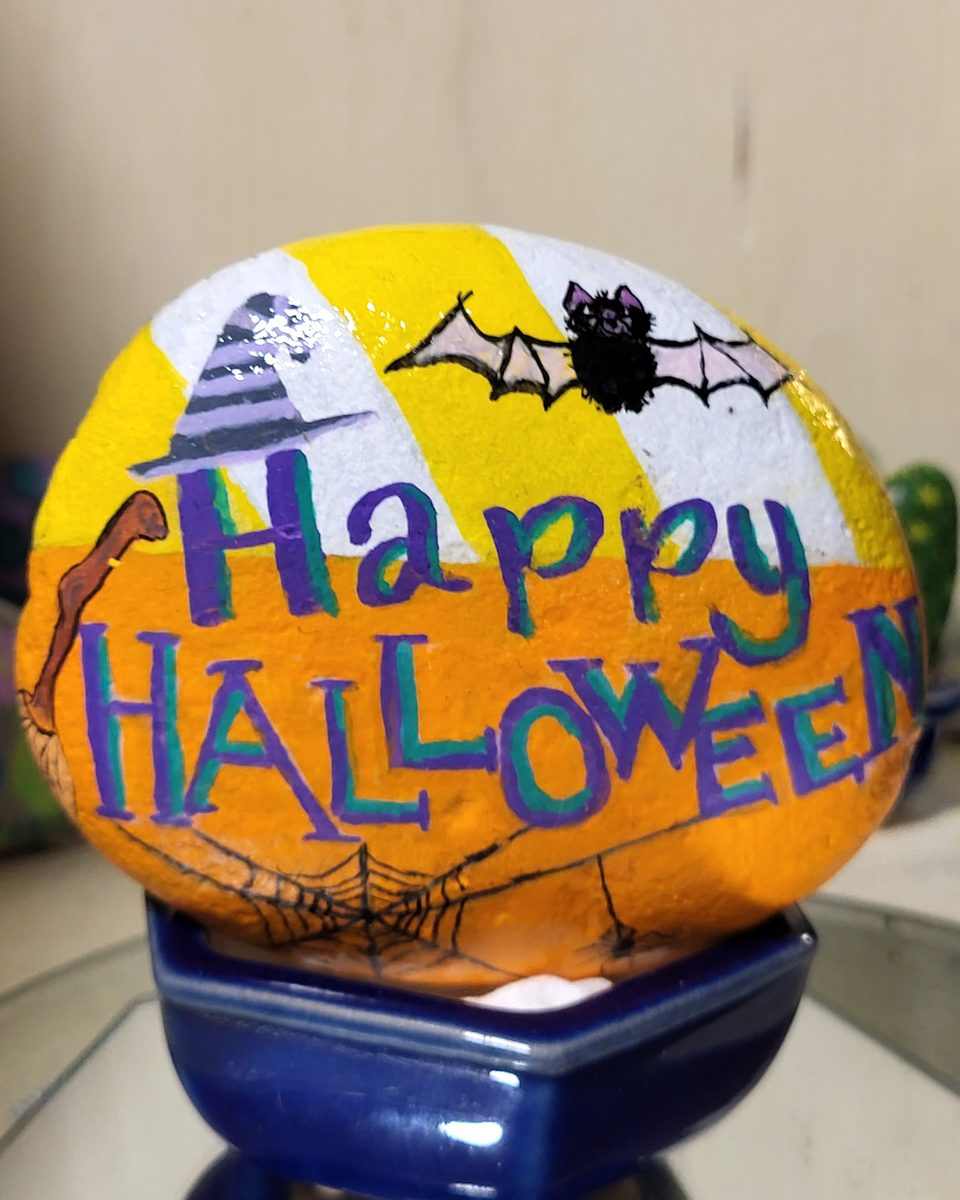 Yellow and orange Happy Halloween stone with a witch hat, bat, and spiderwebs