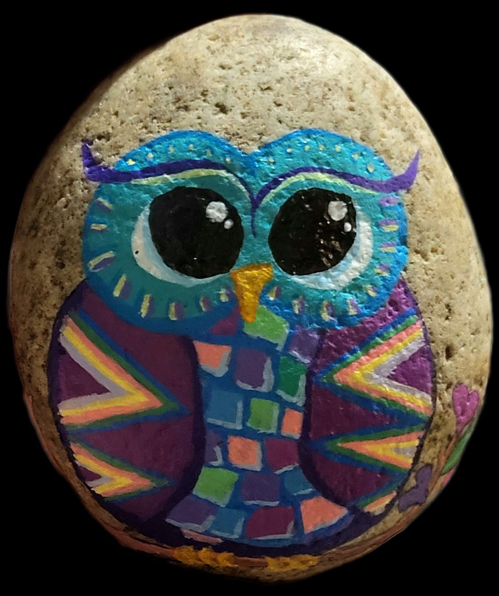 Colorful owl painted with intricate geometric feather designs on natural stone
