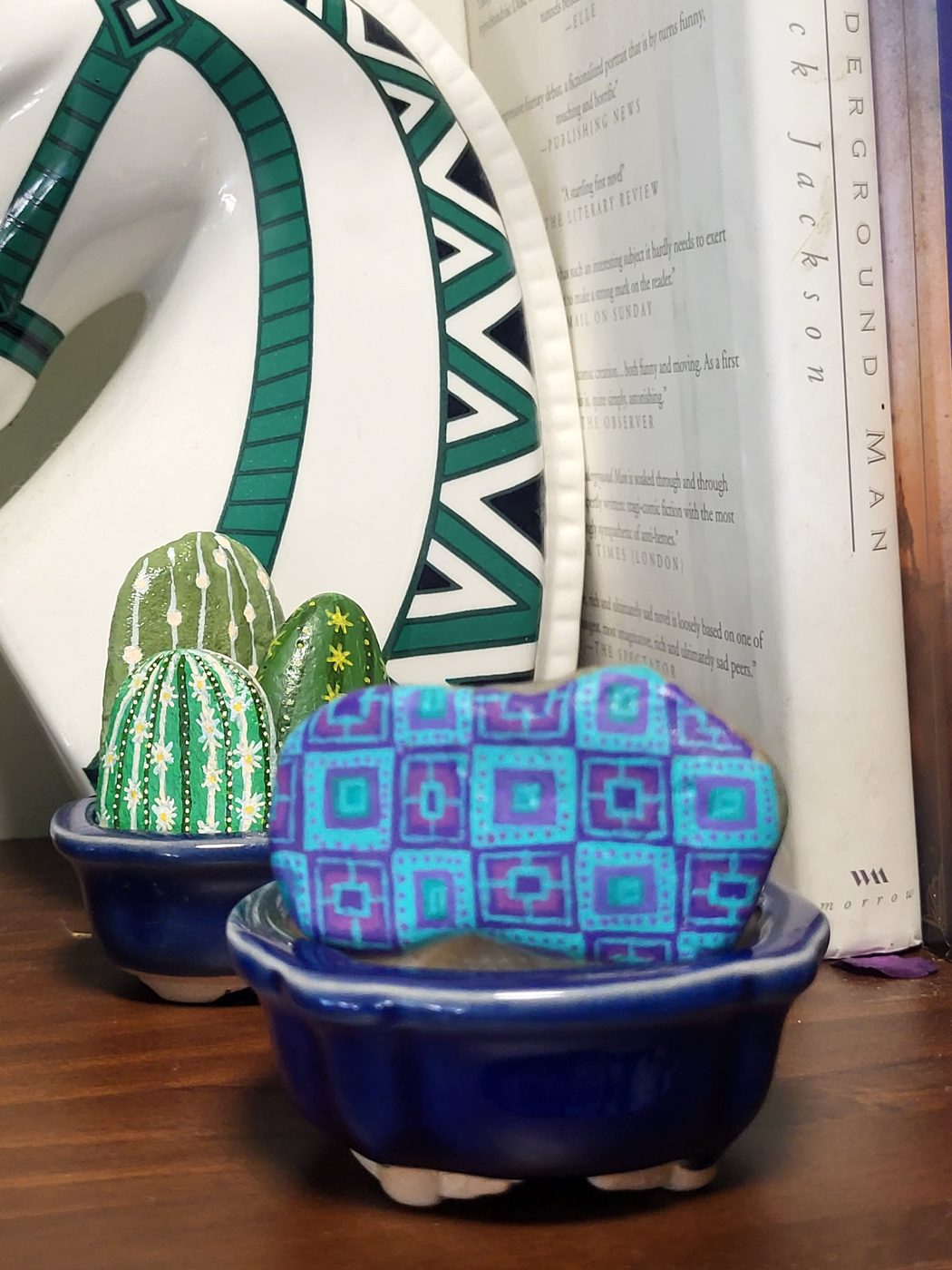 Teal and purple geometric pattern painted on a small rounded stone