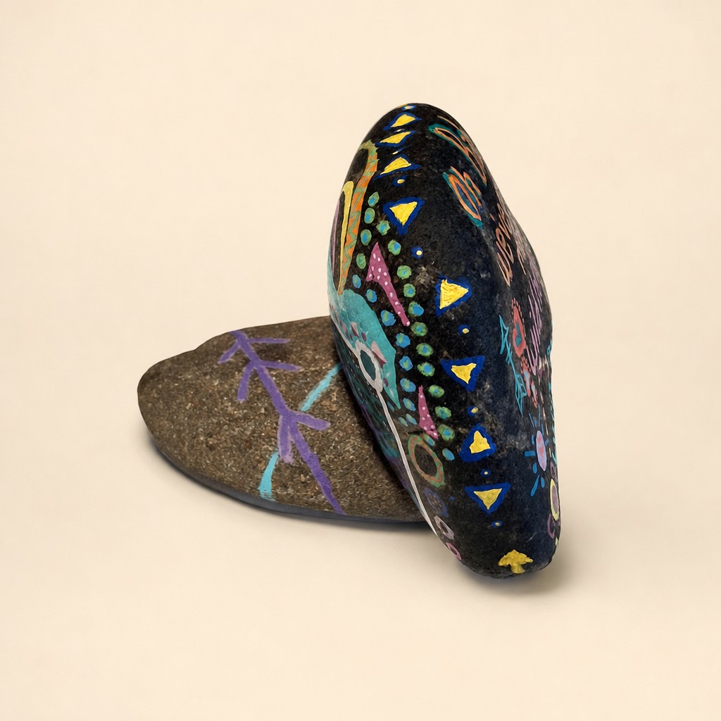 Angled view of the same stacked rock art, showing painted patterns and its stone base