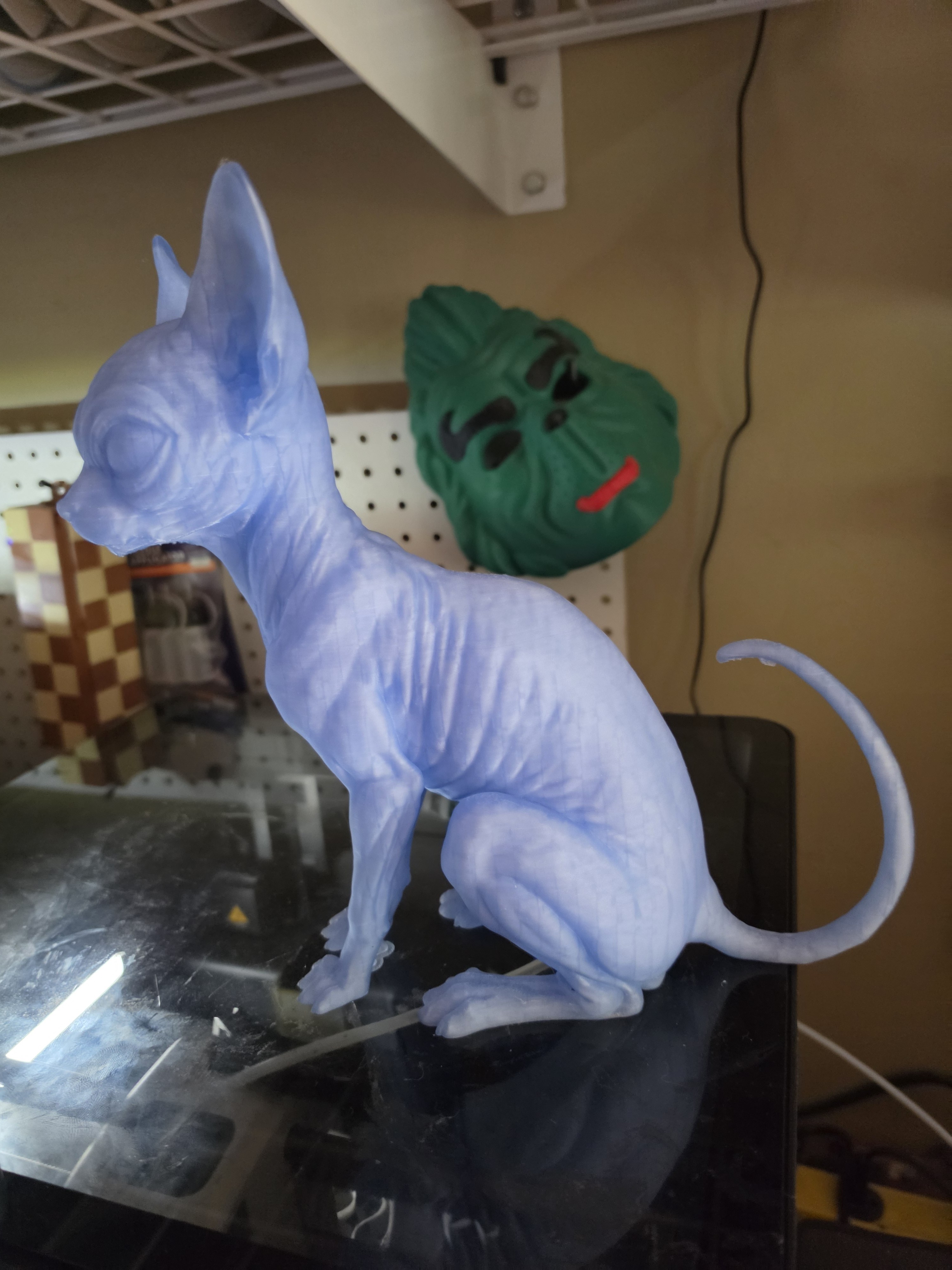 White cat sculpture with green character mask