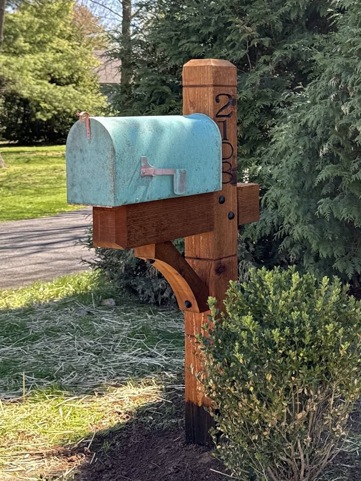 Handcrafted cedar mailbox post with a blue rural mailbox