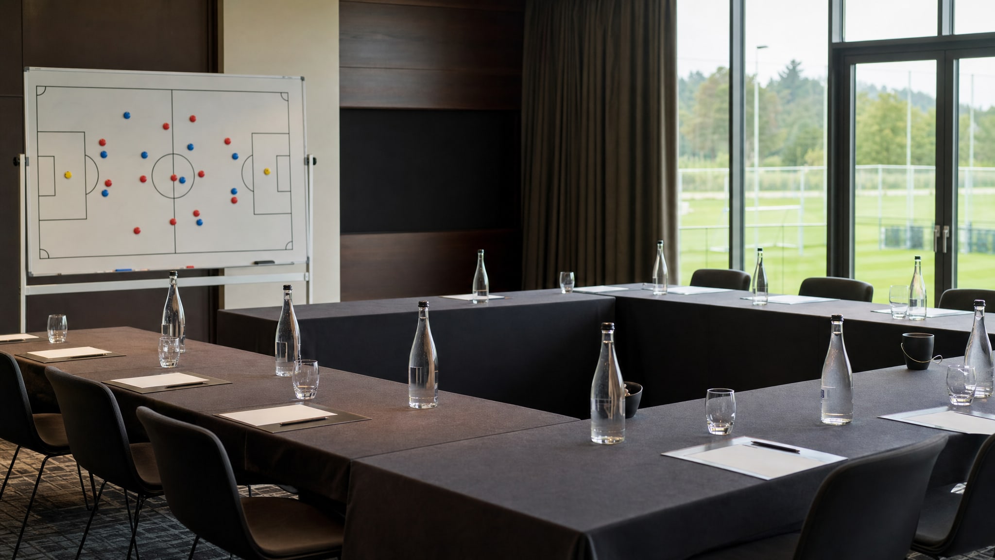 Private football team meeting room with a tactics board overlooking a training pitch