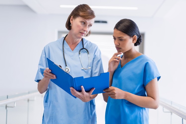 Experienced nurse preceptor reviewing feedback with a new nurse