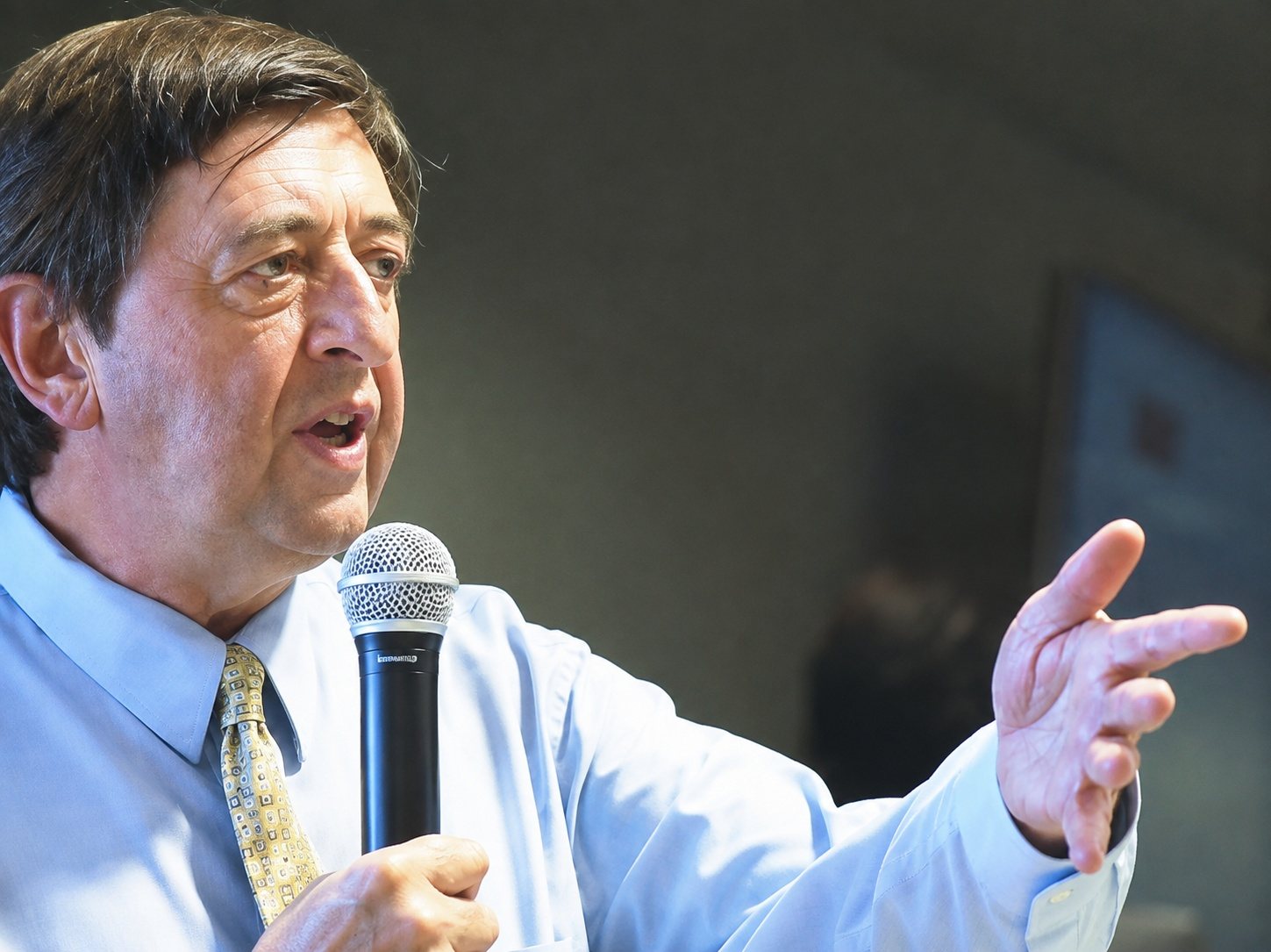 Mark McDonald speaking into a microphone at a conference