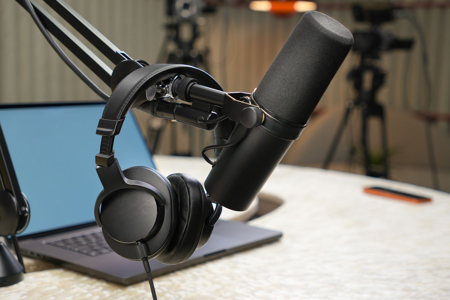 Studio microphone and headphones beside a laptop on a podcast desk