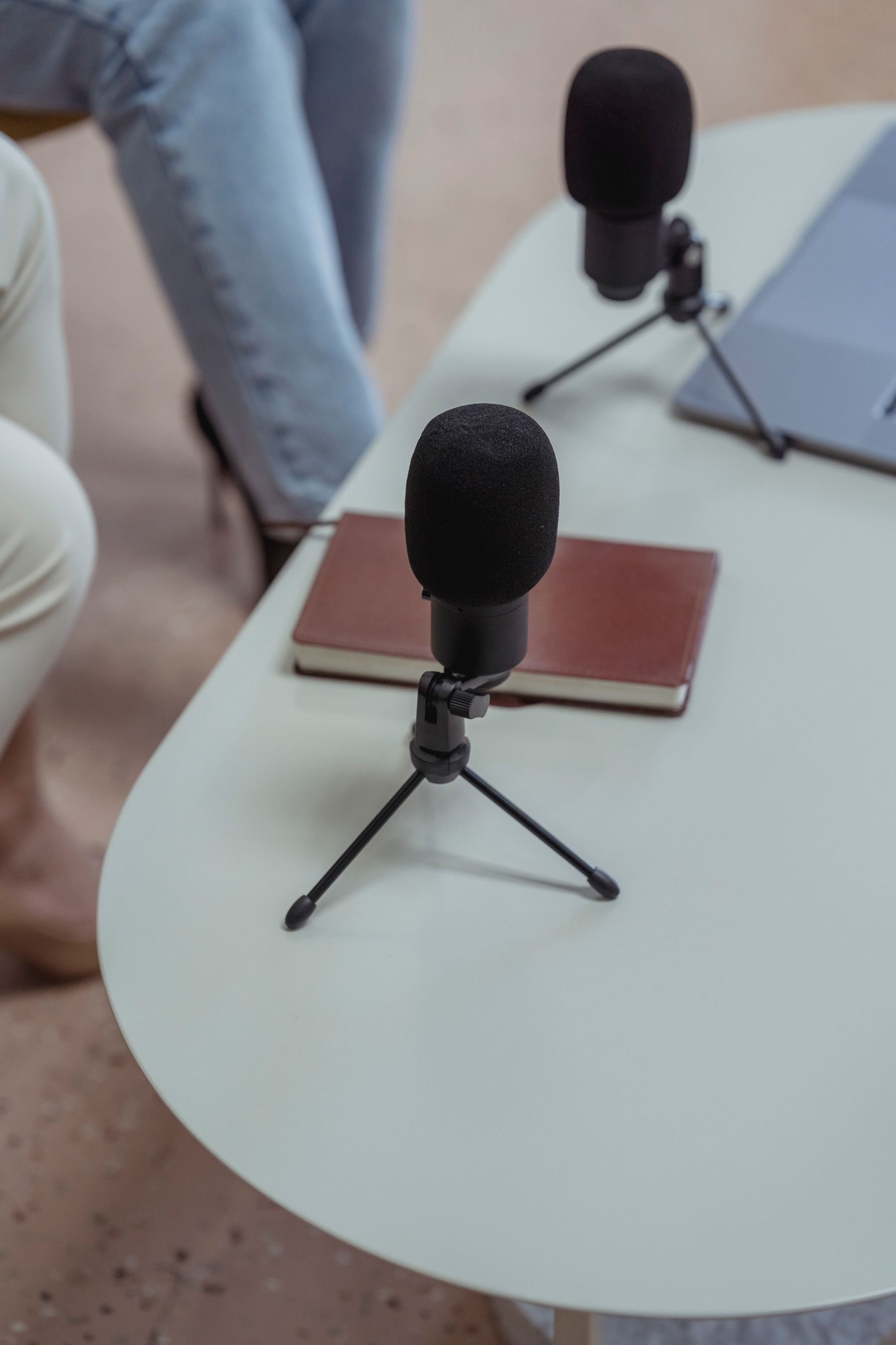 Podcast microphones, notebook, and laptop arranged on a recording table