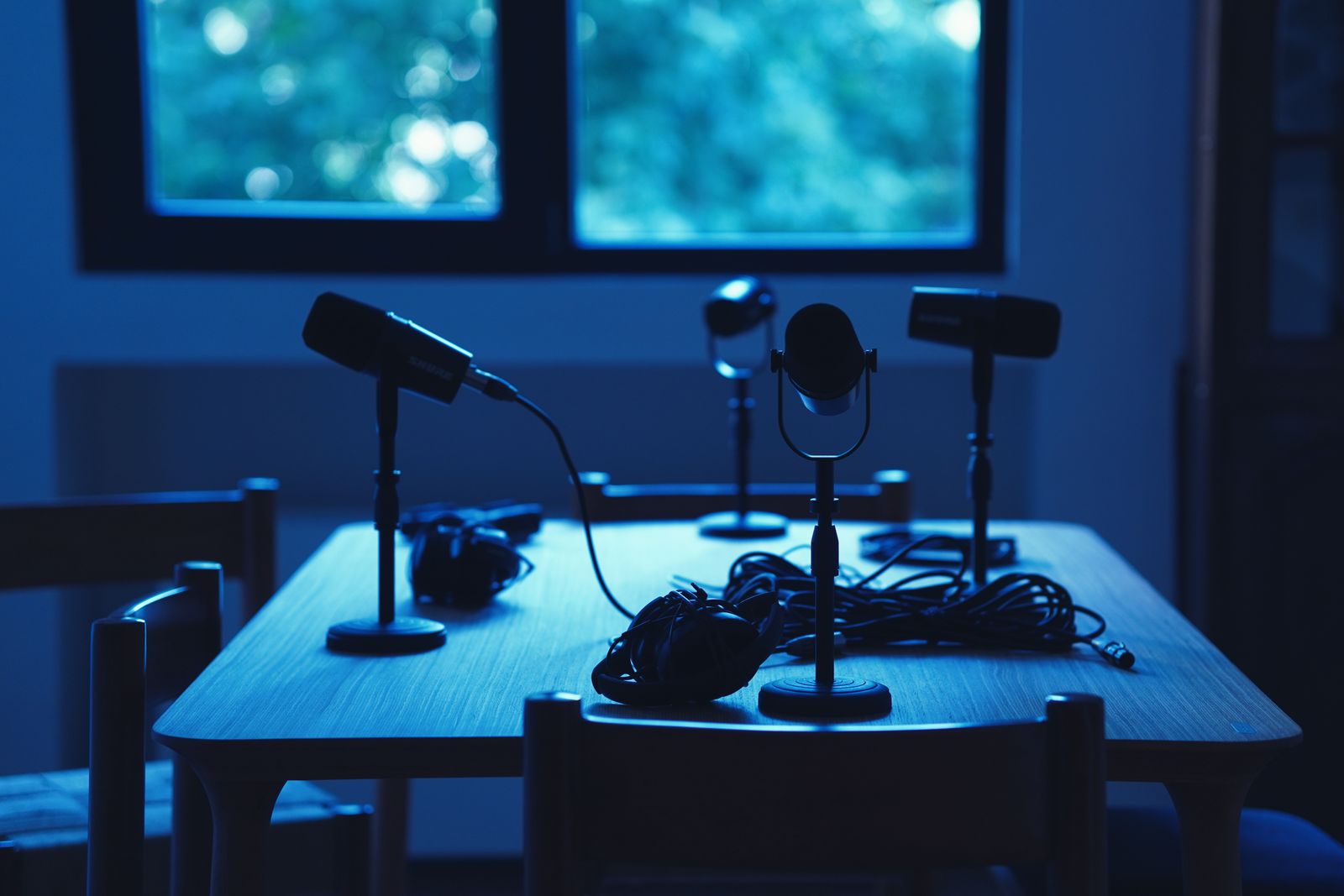 Several microphones and headphones arranged around a podcast studio table