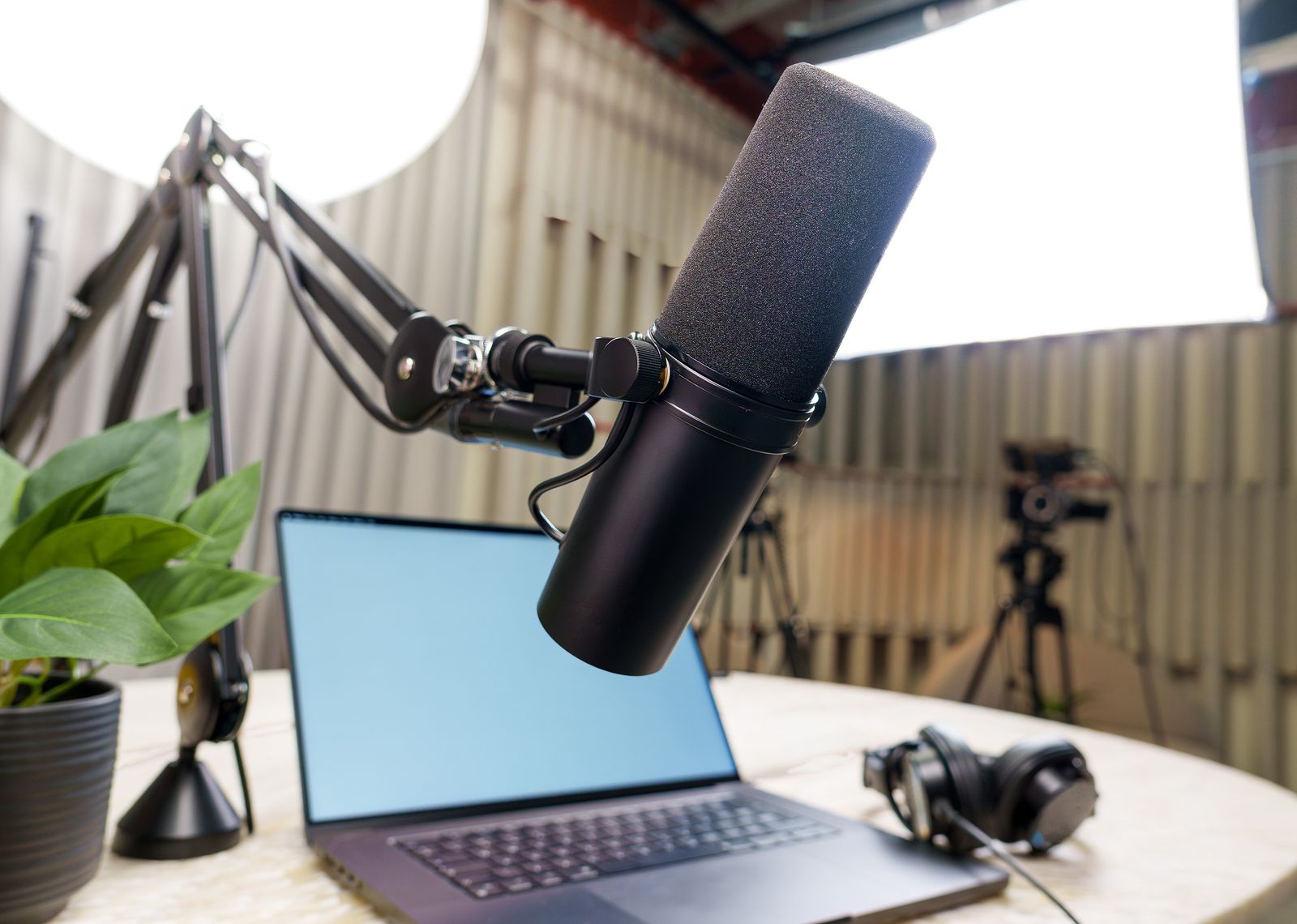 Microphone, headphones and laptop set up for a podcast recording