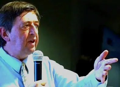 Mark McDonald speaking into a microphone during a presentation