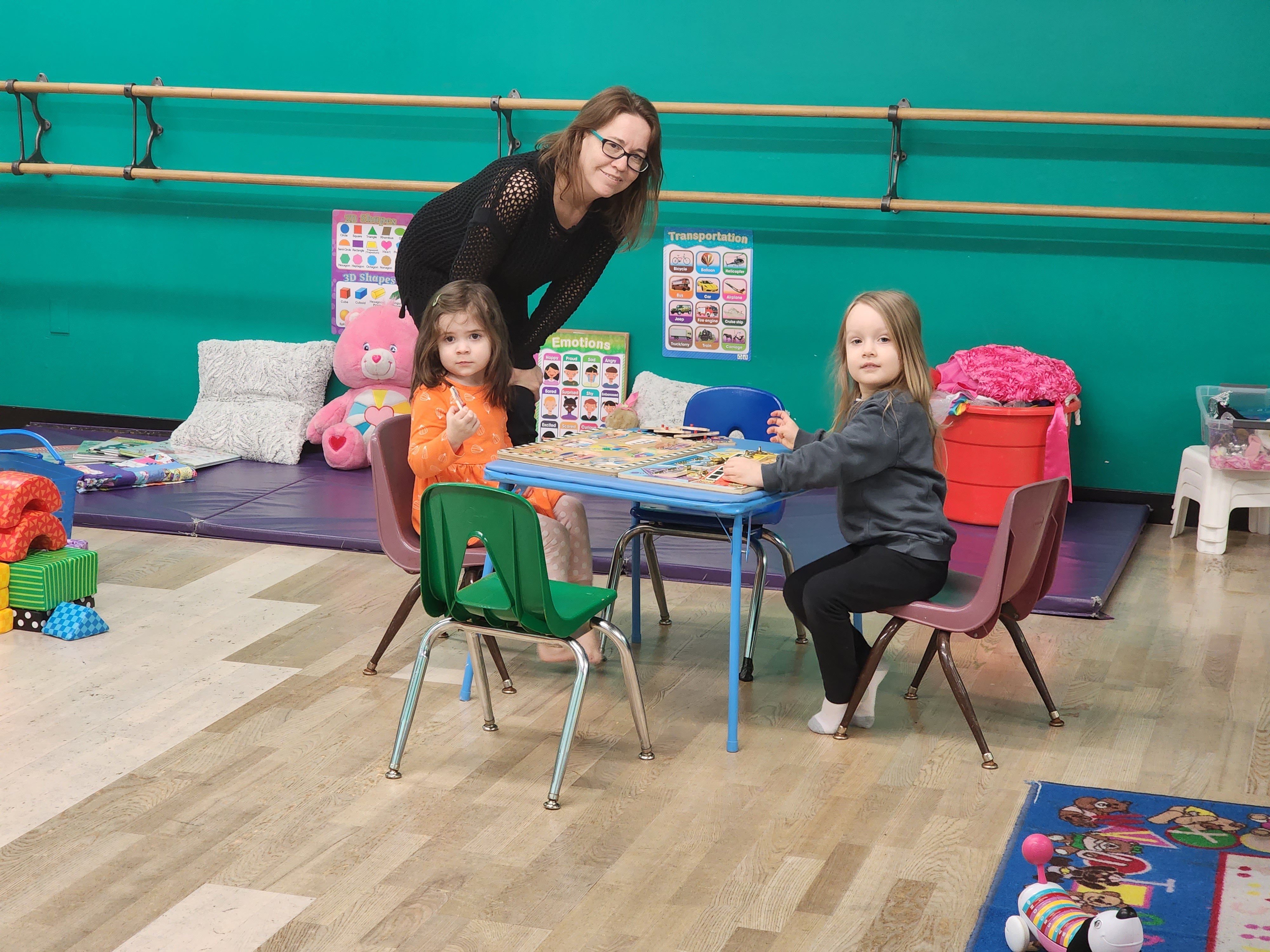 Teacher and preschool children exploring learning materials together in the Rising Stars classroom