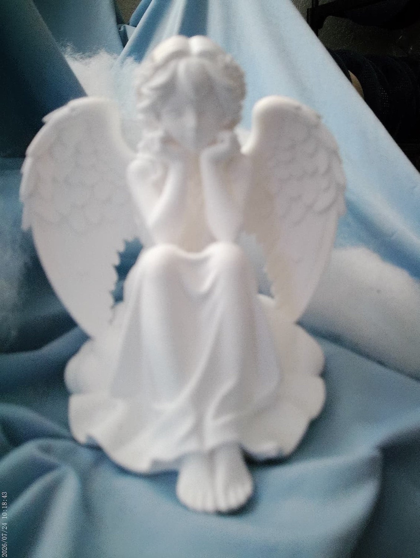 A white contemplative angel figurine with spread wings