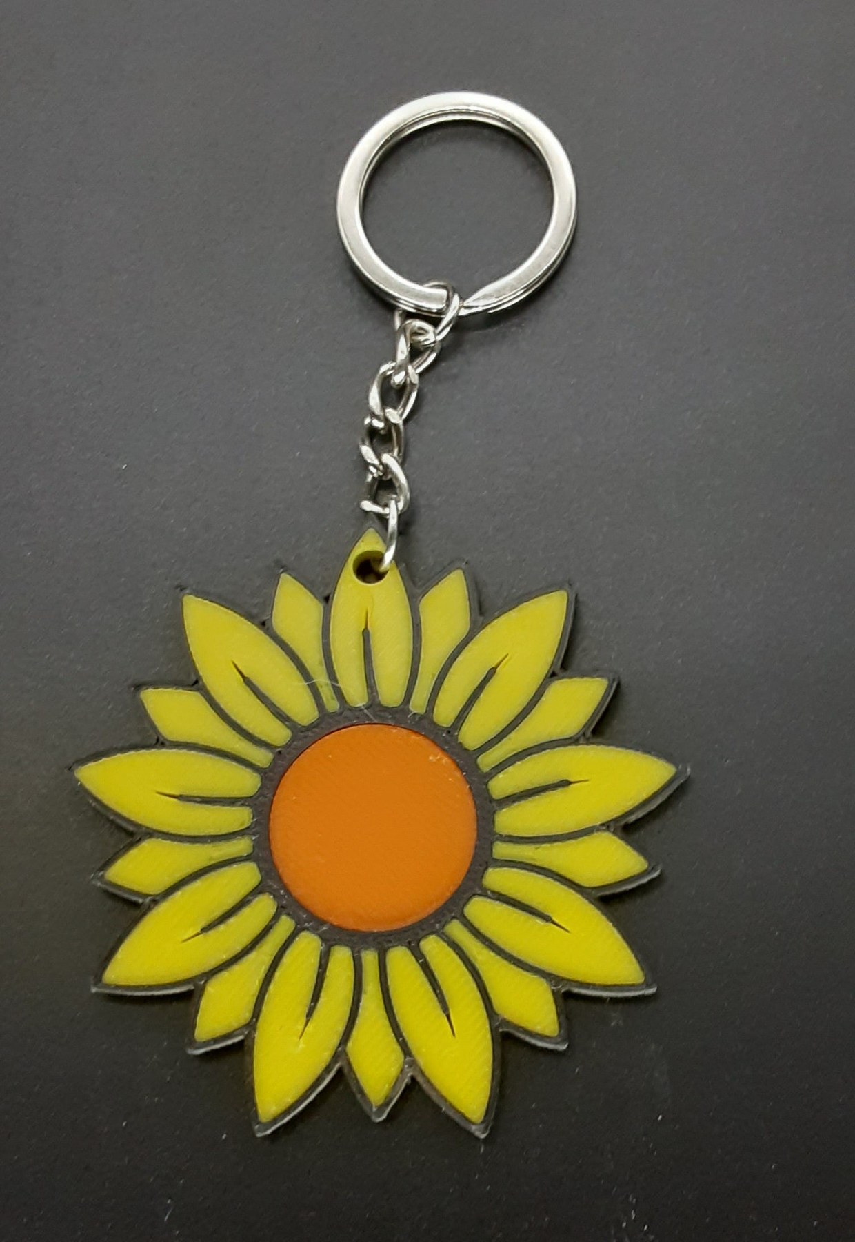 A bright handmade sunflower keychain with layered 3D-printed petals