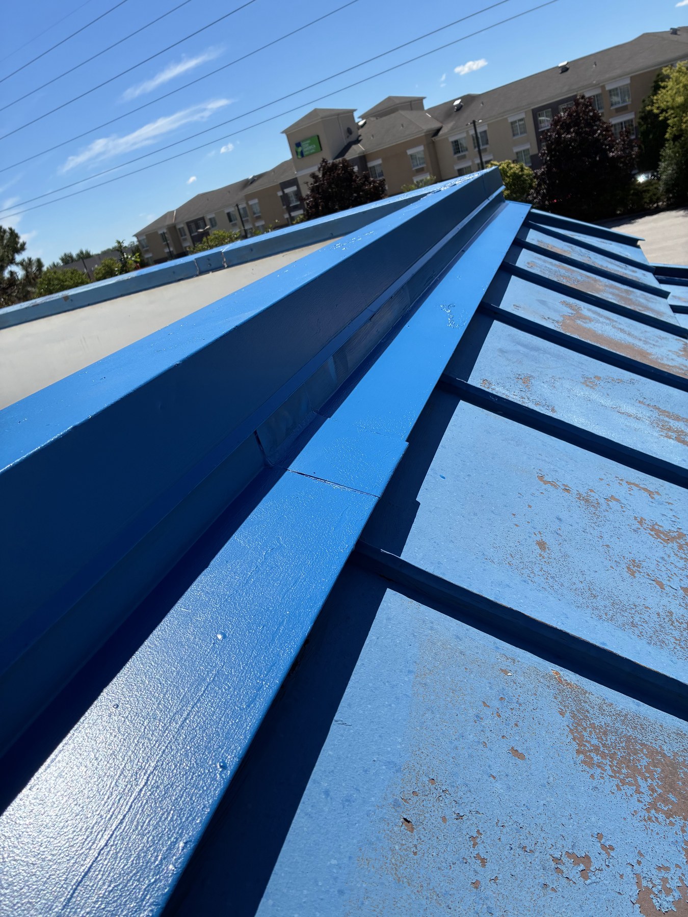 Detailed metal roof preparation beside rooftop equipment