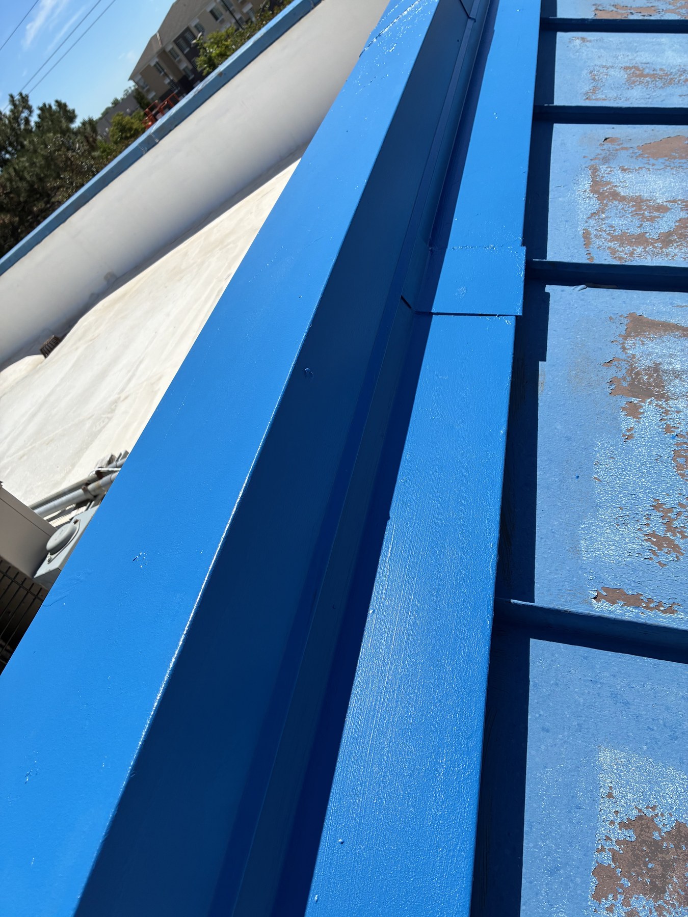 Freshly coated roof ridge beside weathered metal panels