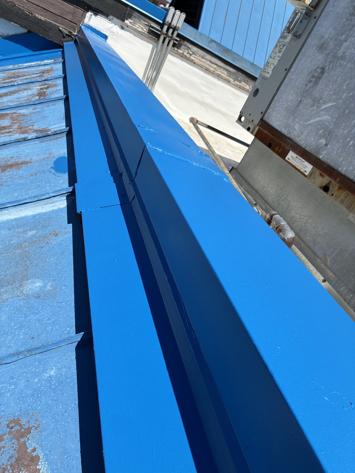 Freshly coated roof ridge with visible metal roof wear