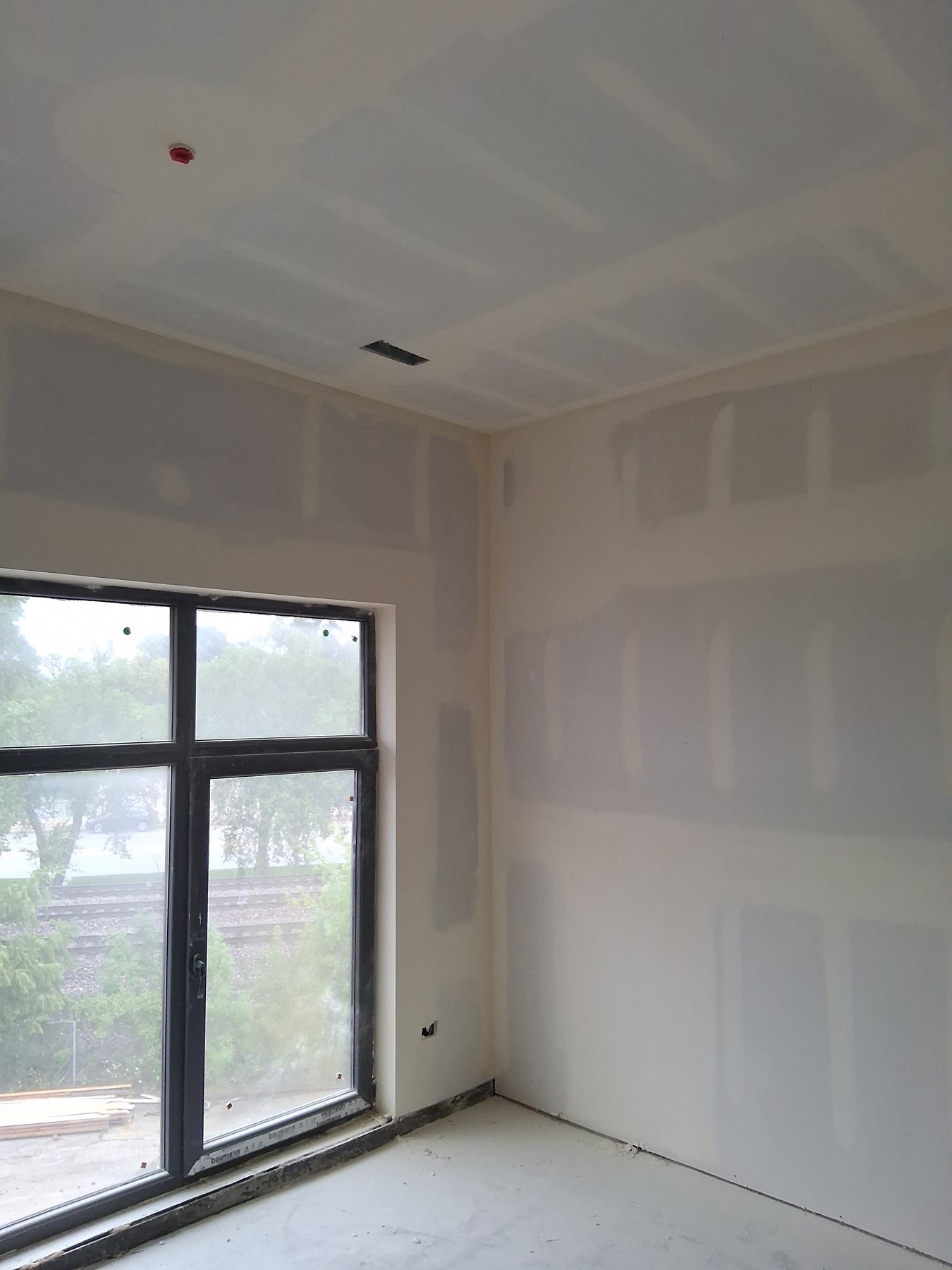 Drywall finishing around tall windows and a ceiling
