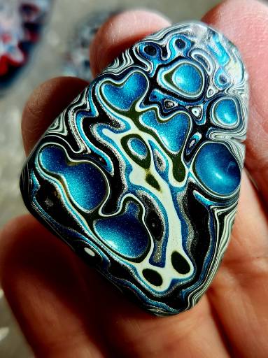 Blue Fordite cabochon with swirling automotive paint layers