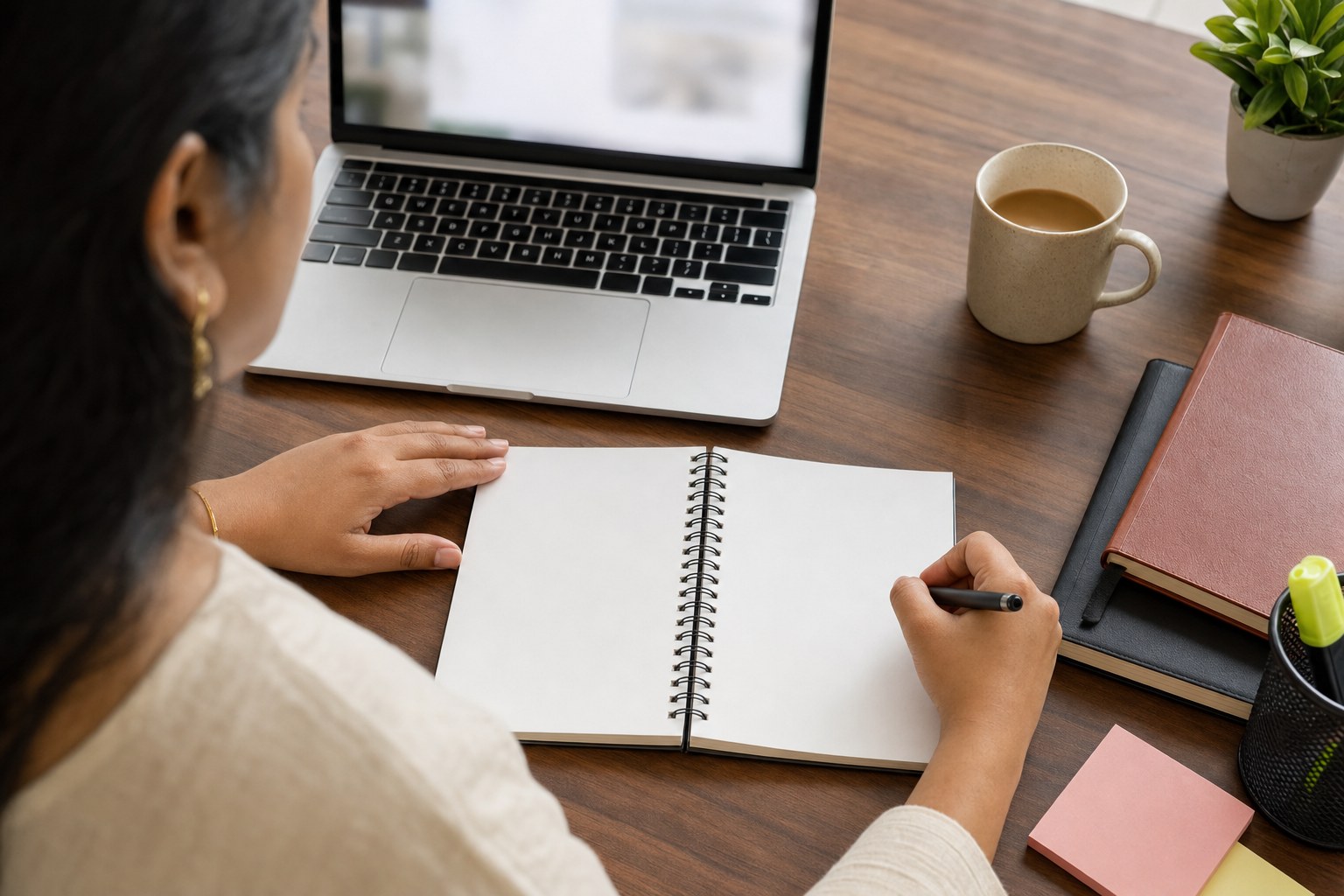 Professional planning a webinar follow-up on a blank notebook beside a laptop