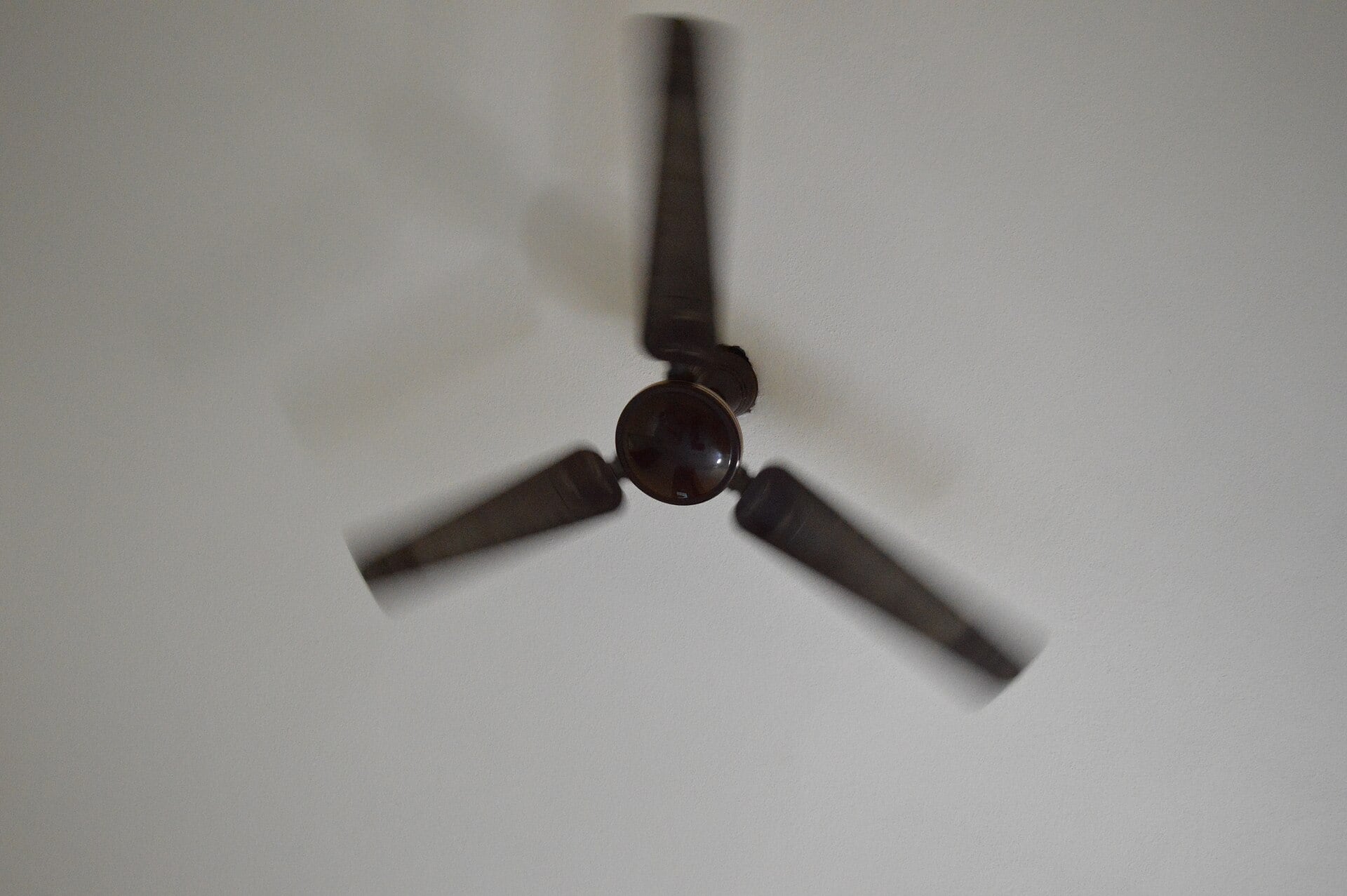 Modern ceiling fan spinning on a residential ceiling