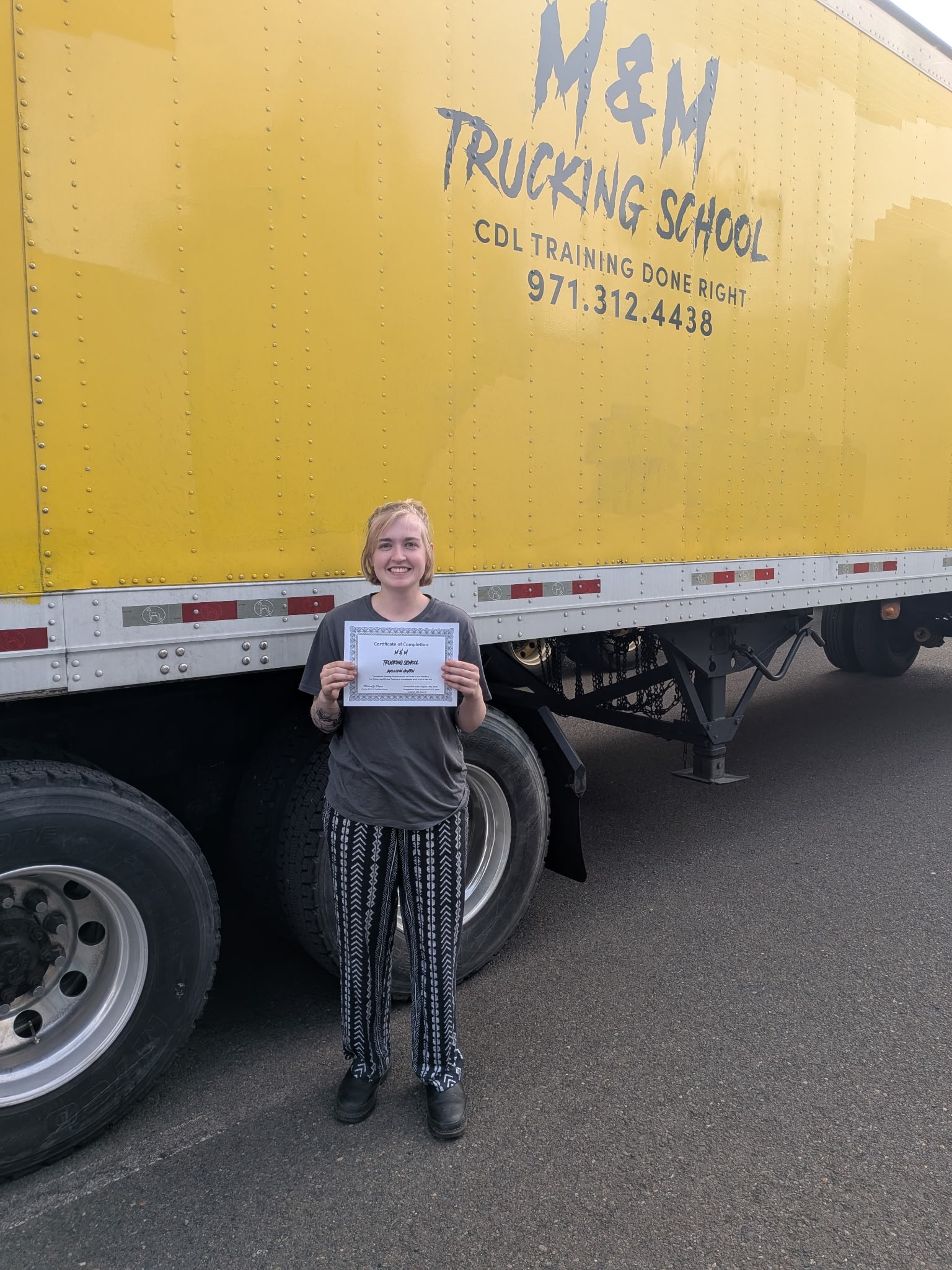 M&M Trucking School graduate standing with a commercial training truck
