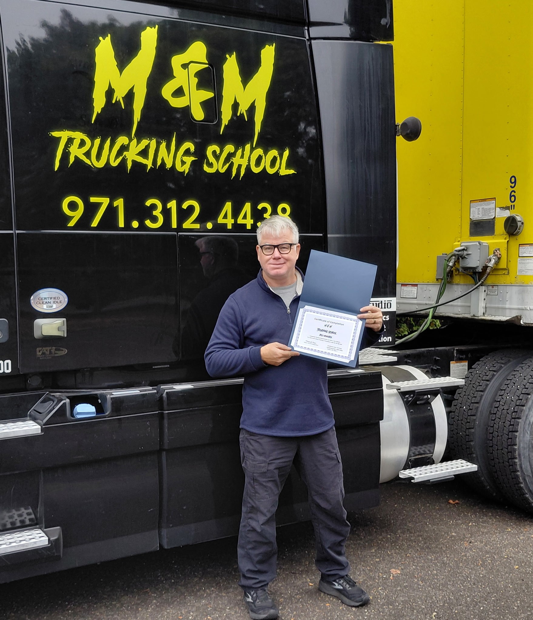 M&M Trucking School graduate beside a tractor-trailer
