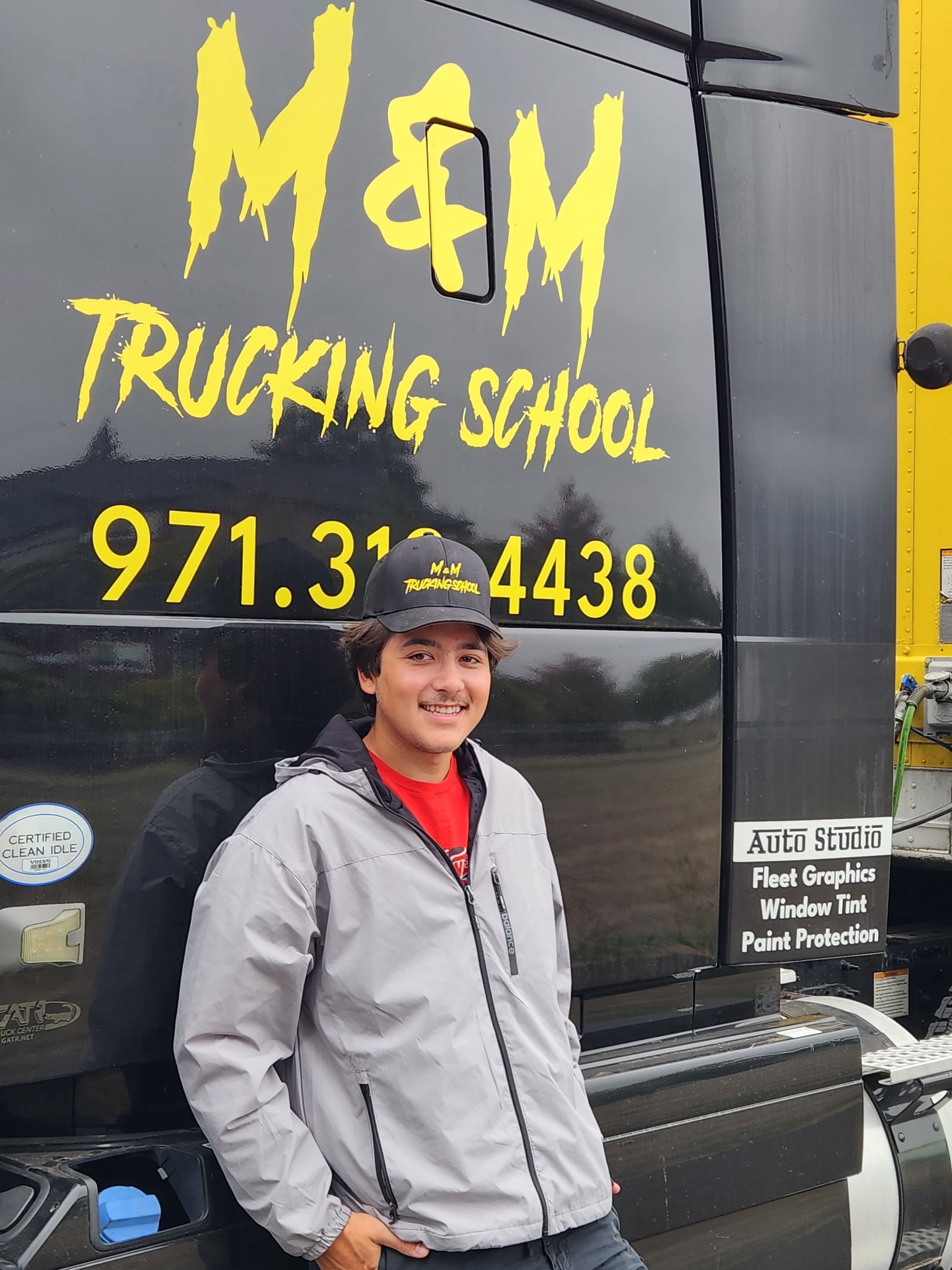 M&M Trucking School graduate standing beside an M&M training truck