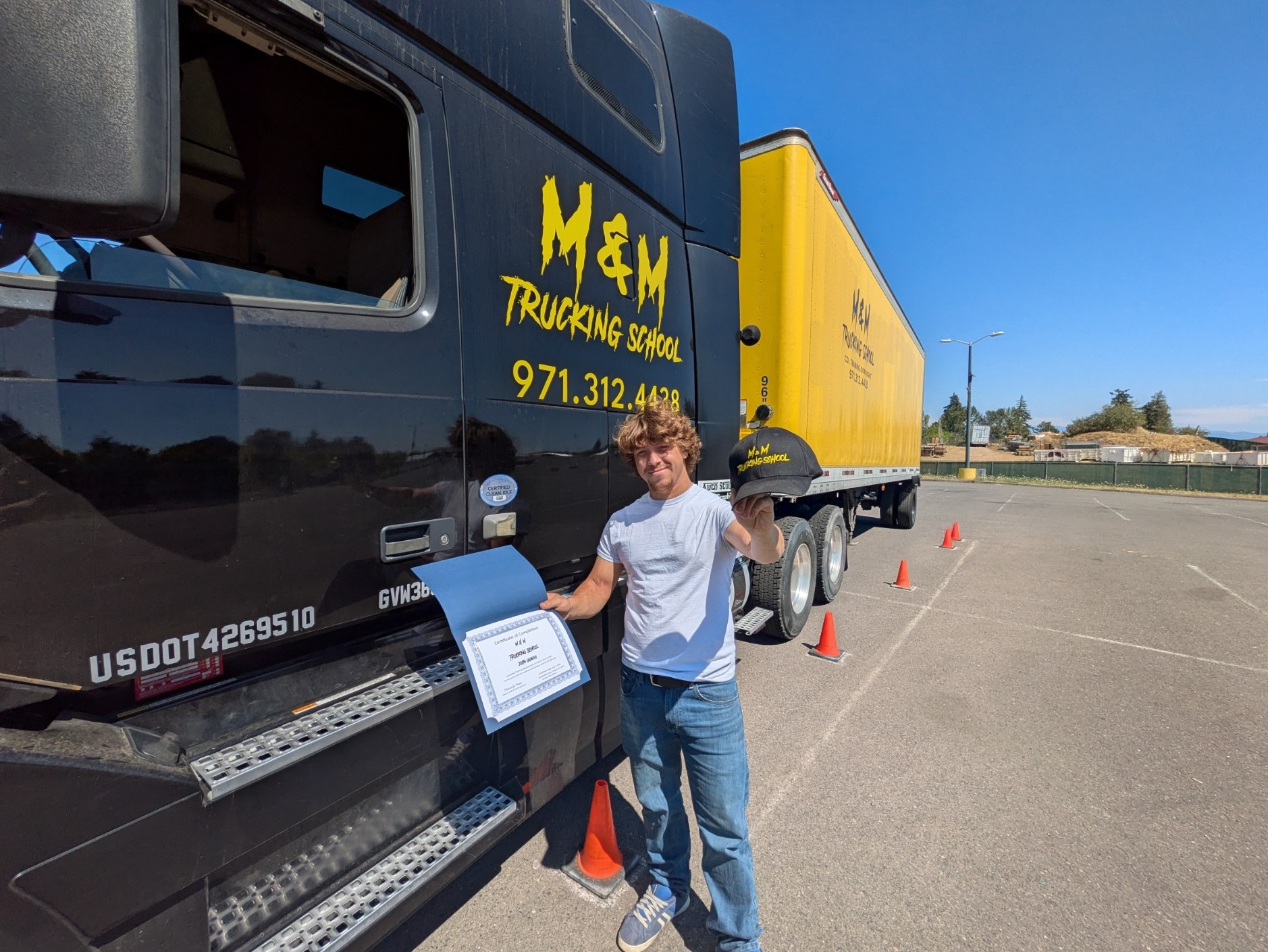 Justin celebrating his M&M Trucking School graduation beside a training truck