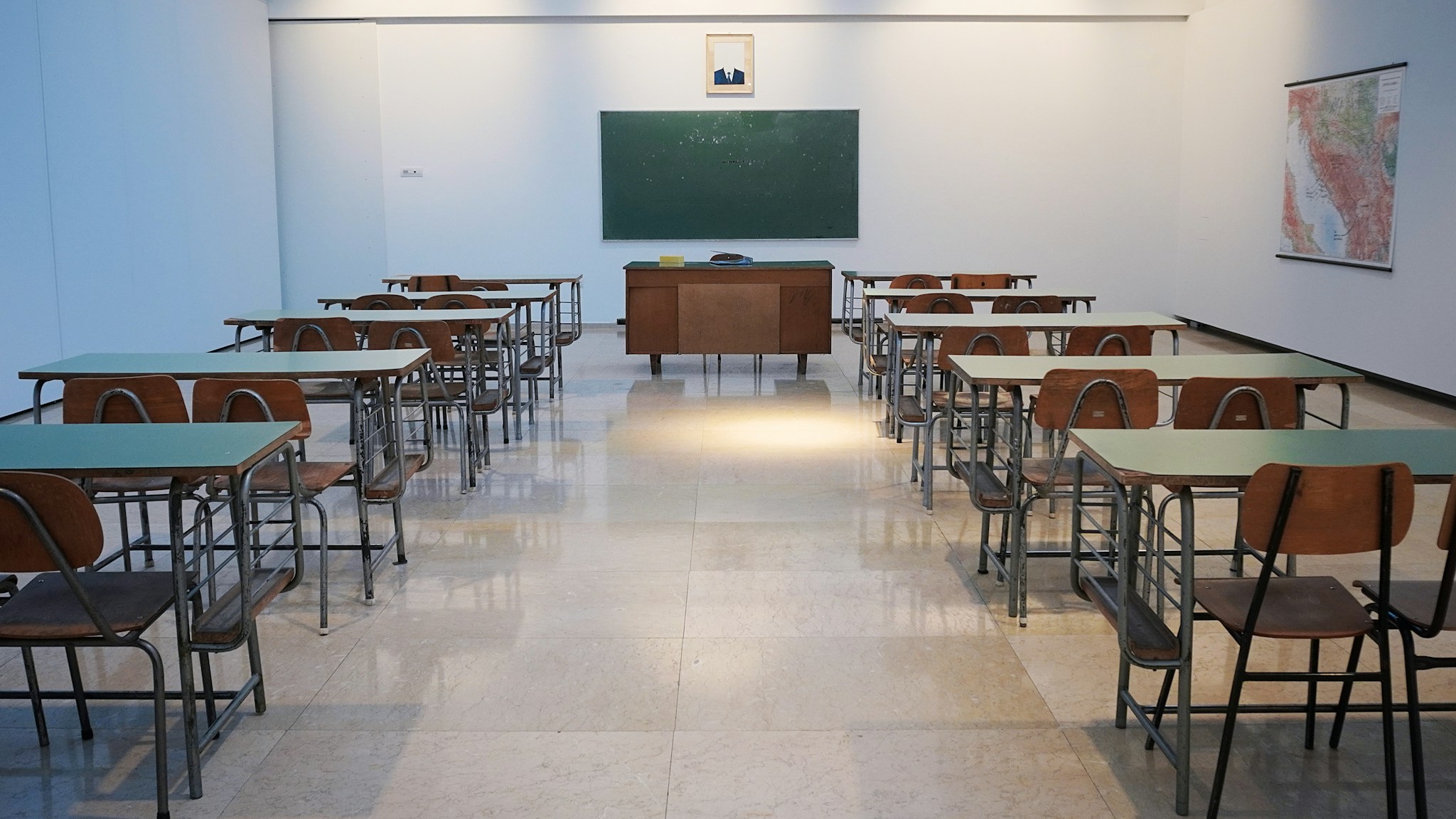 Quiet classroom with desks, chalkboard, and a map on the wall
